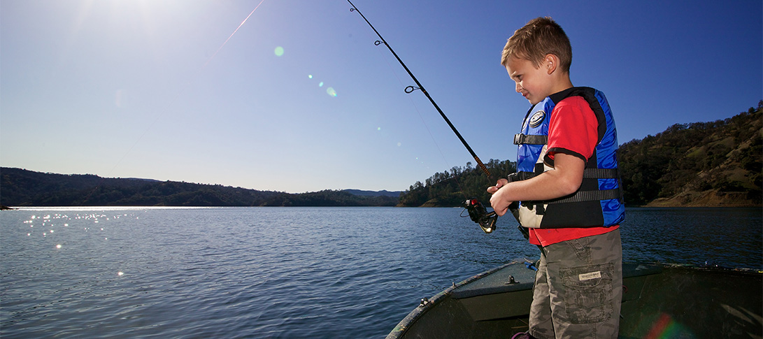 photo: a young fisher wearing a life jacket operates a reel