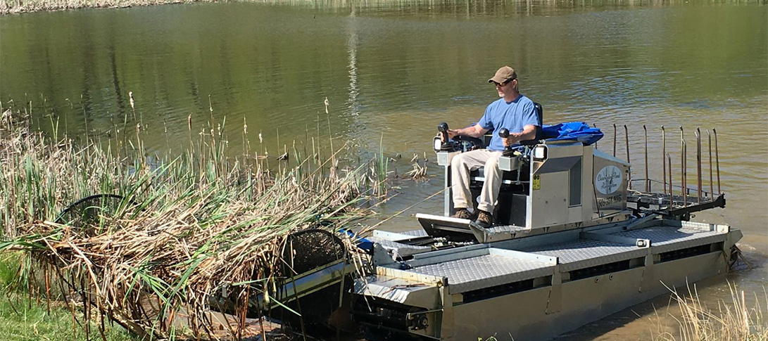 photo: a technician operates a large machine performing pond maintenance