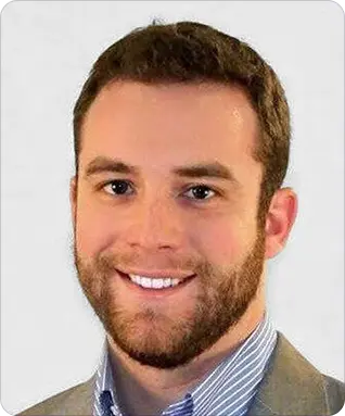 A man with short brown hair and a beard, wearing a light-colored suit jacket and a striped shirt, smiles at the camera against a plain background, reflecting confidence in stormwater management.