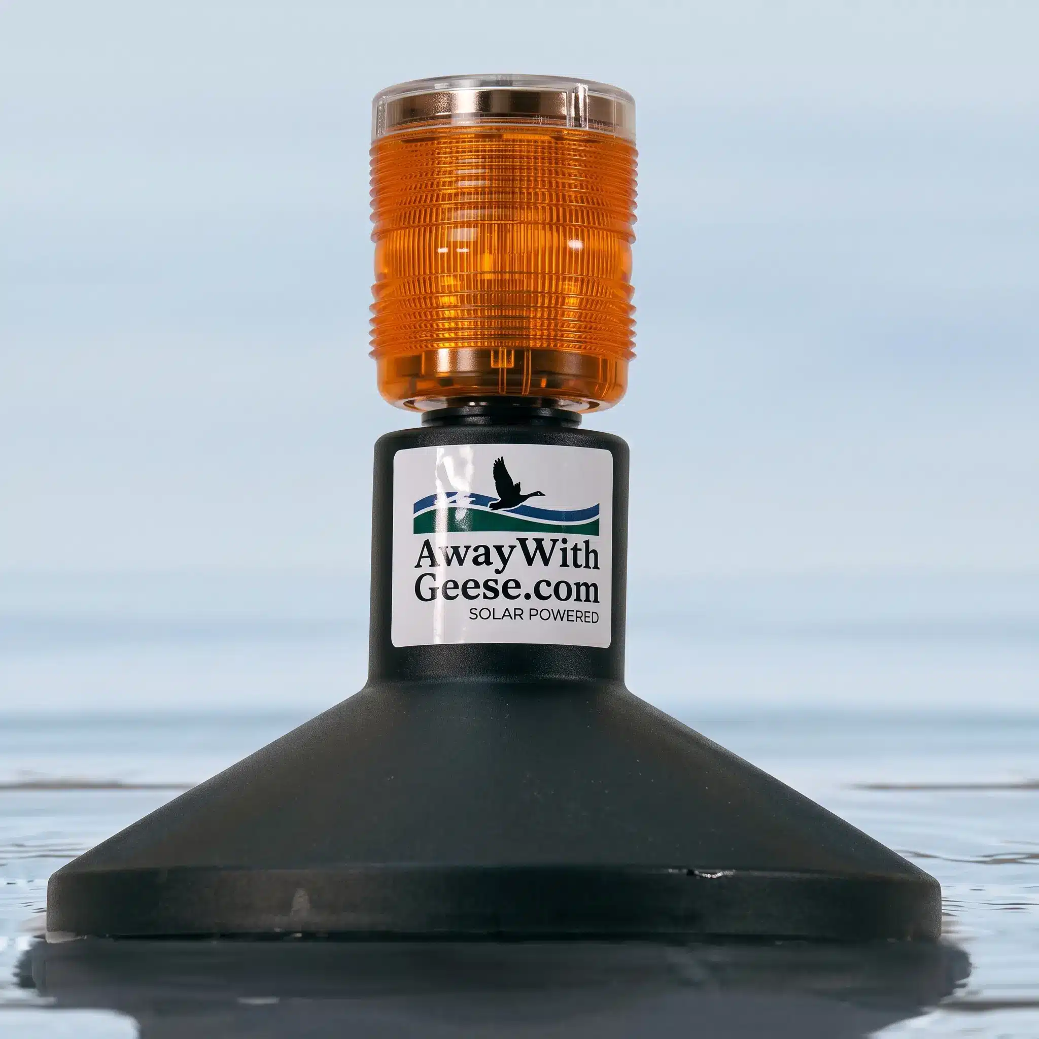 A floating solar-powered light device with an orange beacon labeled “AwayWithGeese.com” on a calm water surface.